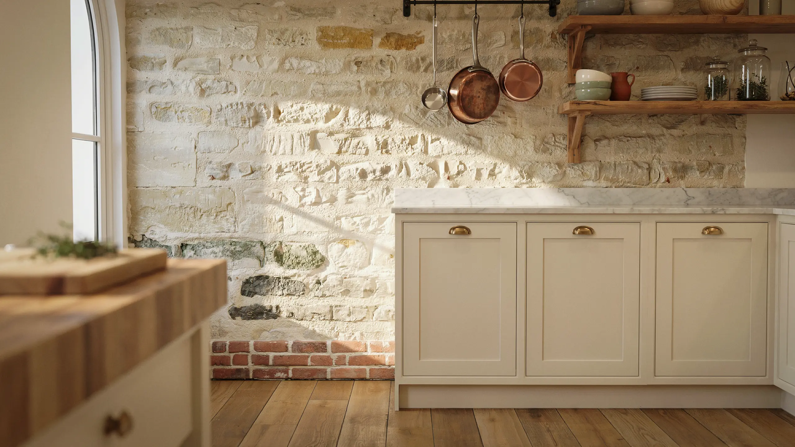 French country kitchen with exposed stone and brick accent wall adding texture and rustic character behind cream cabinets.