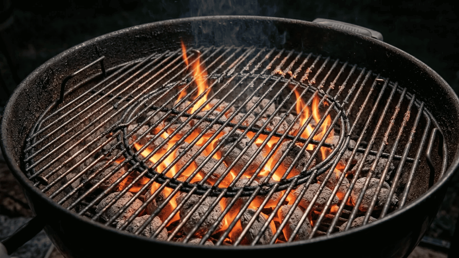 Grill grates heating over open charcoal flames inside a round outdoor barbecue grill.