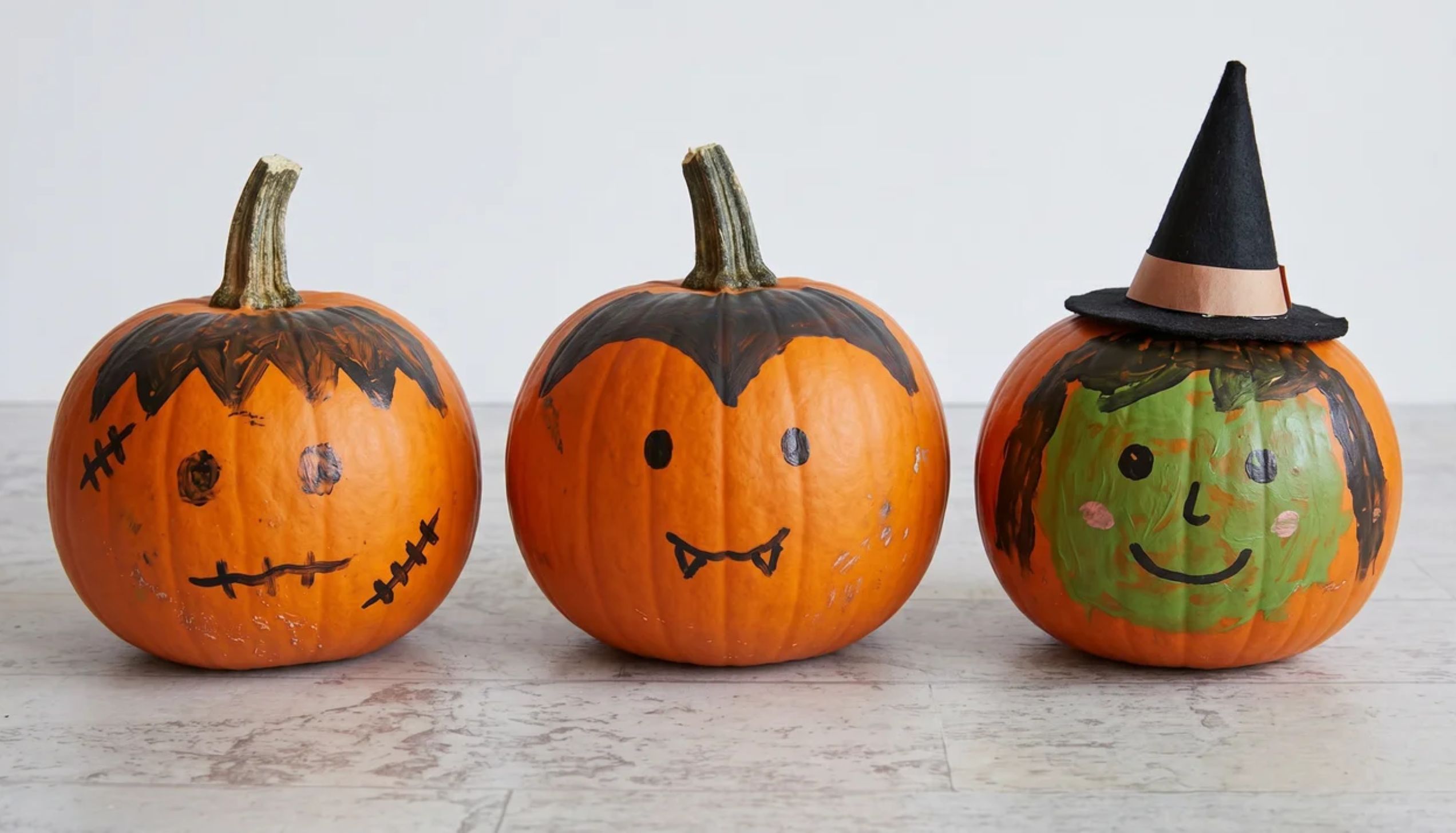 Three hand-painted Halloween pumpkins, inspiring ideas for easy thanksgiving crafts.