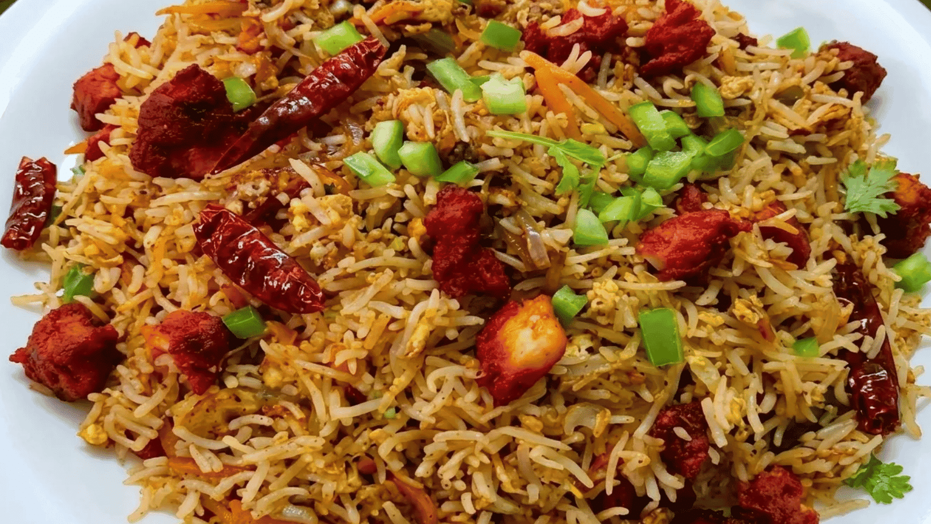 Chicken fried rice with crispy rice, eggs, vegetables, and spicy chicken pieces topped with green onions.