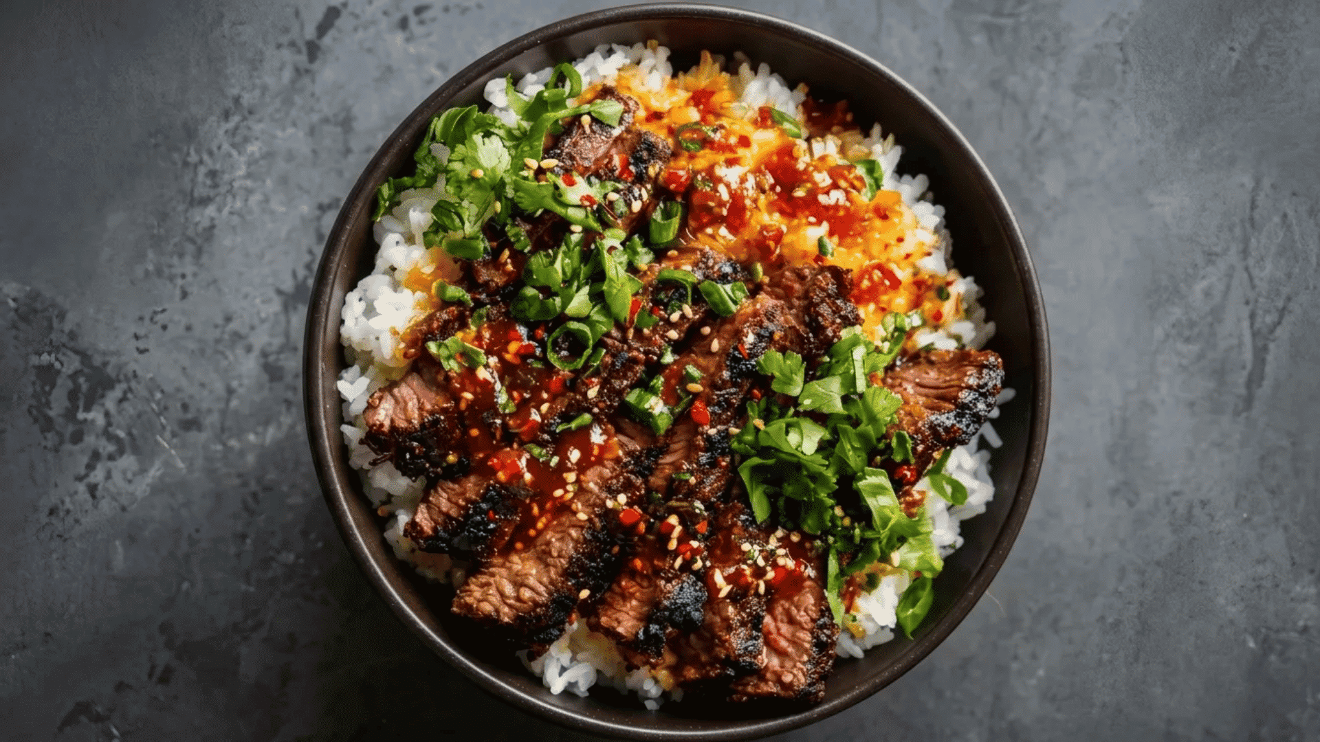 Korean BBQ bowl with grilled beef, steamed rice, spicy sauce, sesame seeds, and fresh herbs.