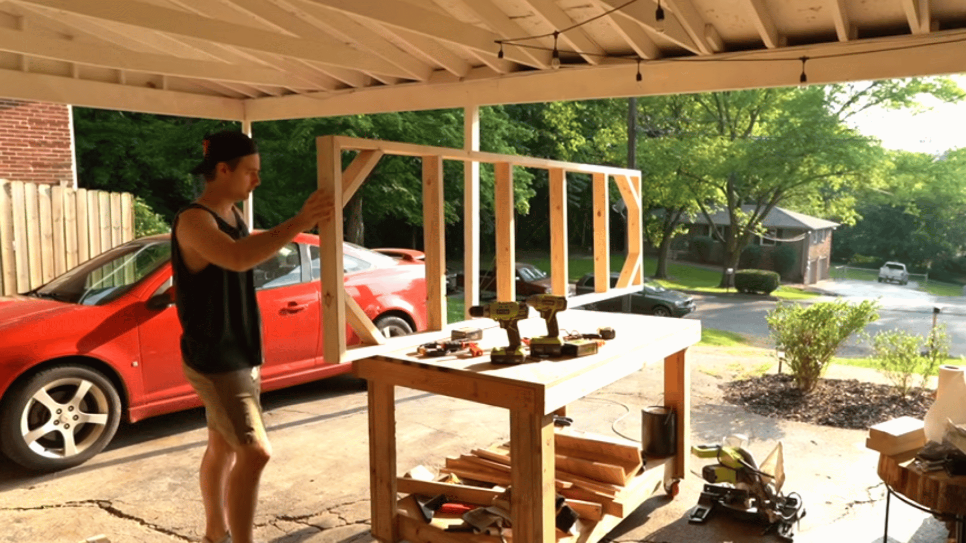 man-lifting-a-completed-rectangular-wooden-table-base-frame-in-an-open-garage