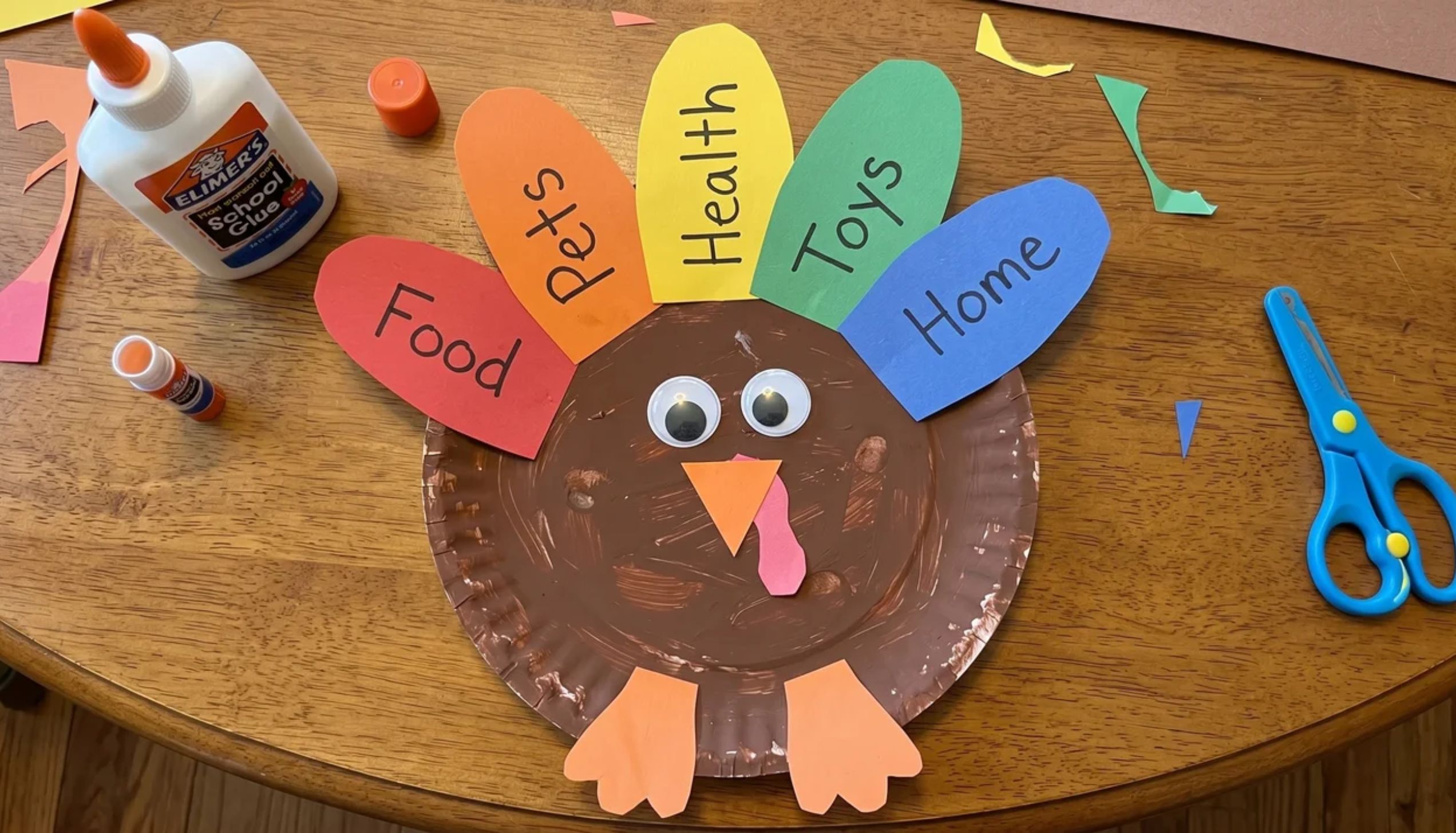 Brown paper plate turkey with colorful construction paper feathers hung on a door as a easy Thanksgiving crafts for kids