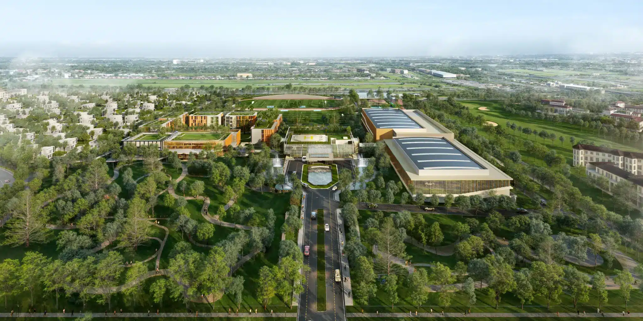Aerial view of expansive green landscape with modern buildings, pathways, and parking area in the foreground