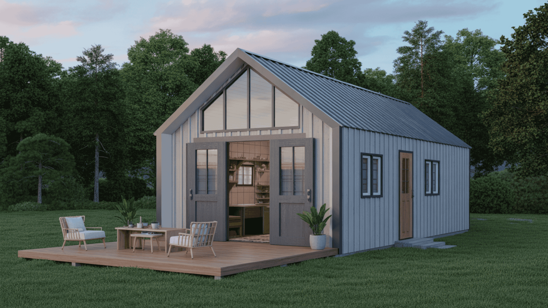 A small, modern one-story barndominium with light gray vertical siding, a front glass facade, and a wooden deck with a small patio table.