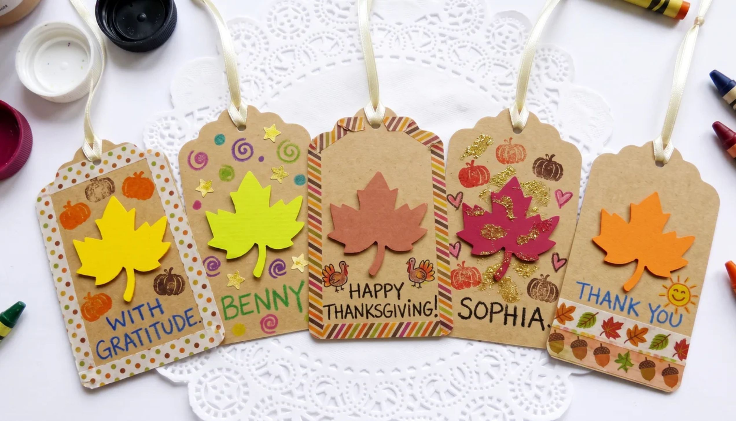 Five decorated paper gift tags with fall leaves and names, perfect for easy thanksgiving crafts.