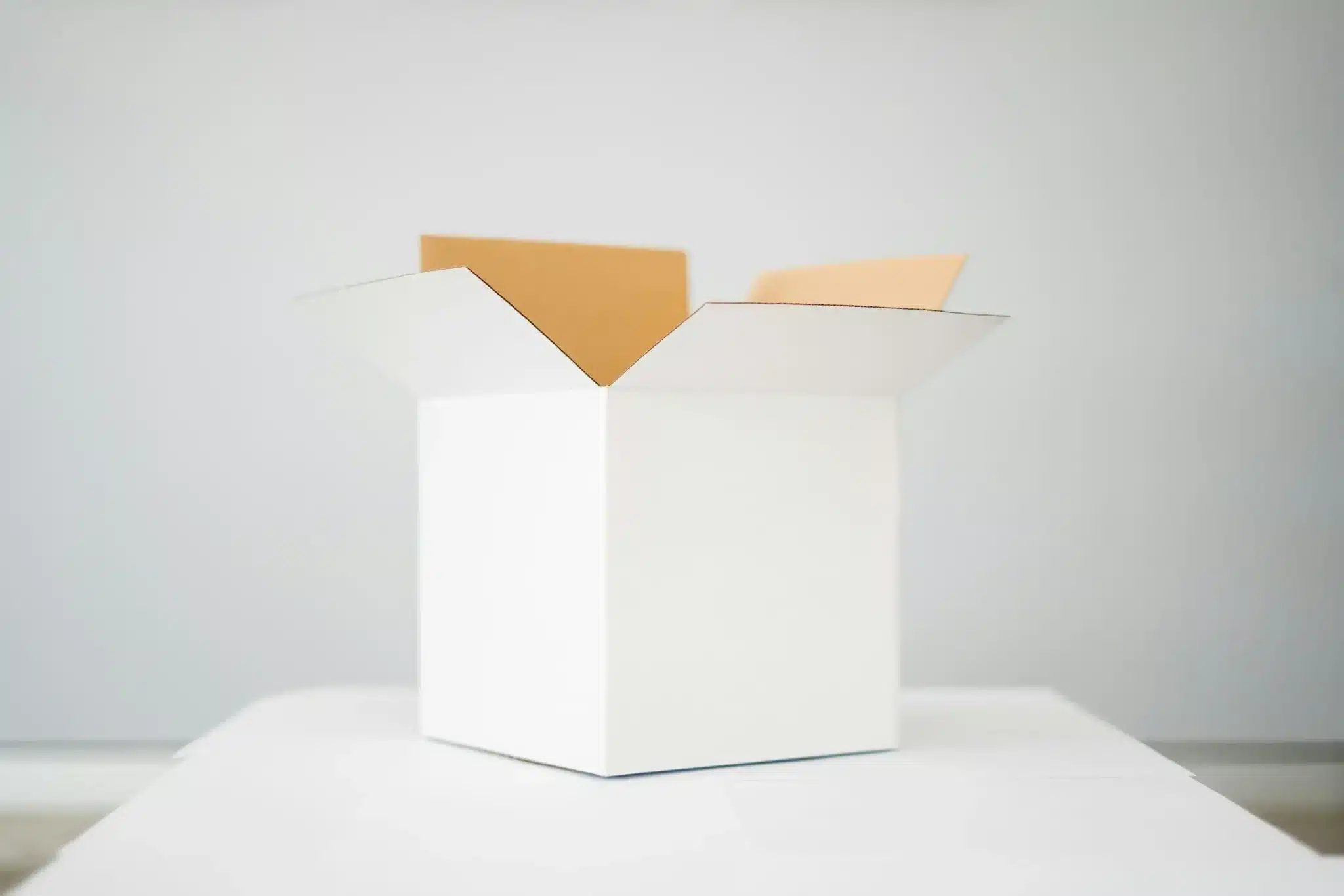 Open white cardboard box on a table in a minimalistic indoor setting