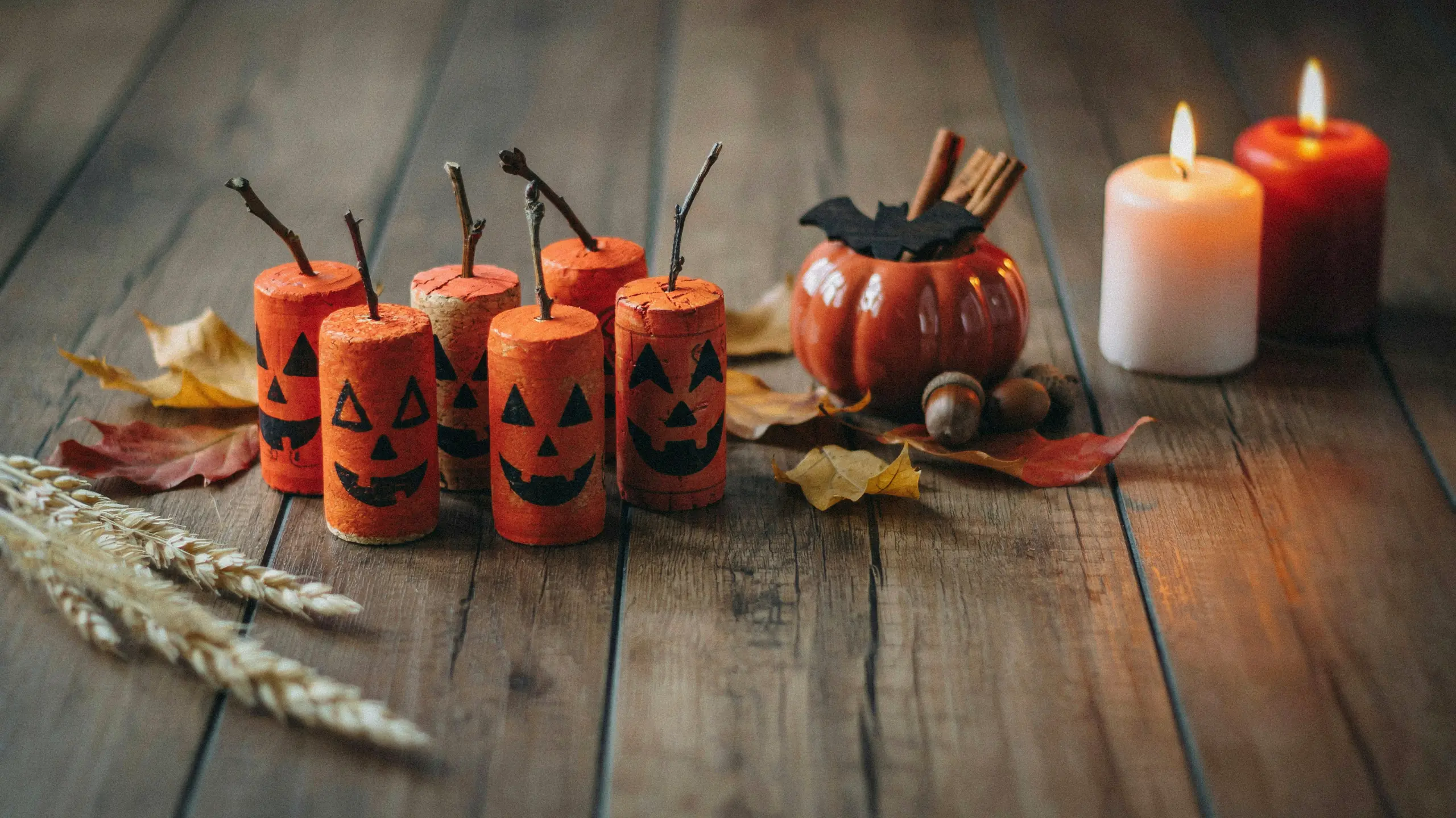 Wine cork Halloween pumpkins with painted faces on rustic table.