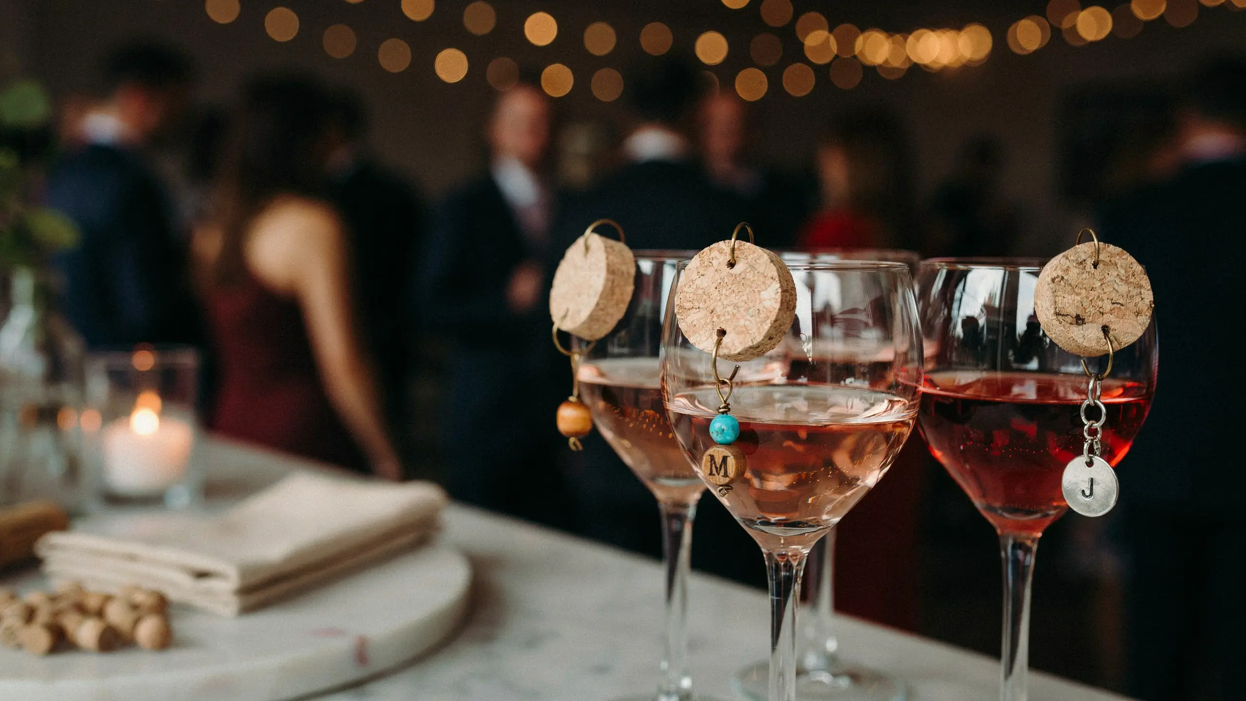 Wine glasses with handmade wine cork charms at party table.