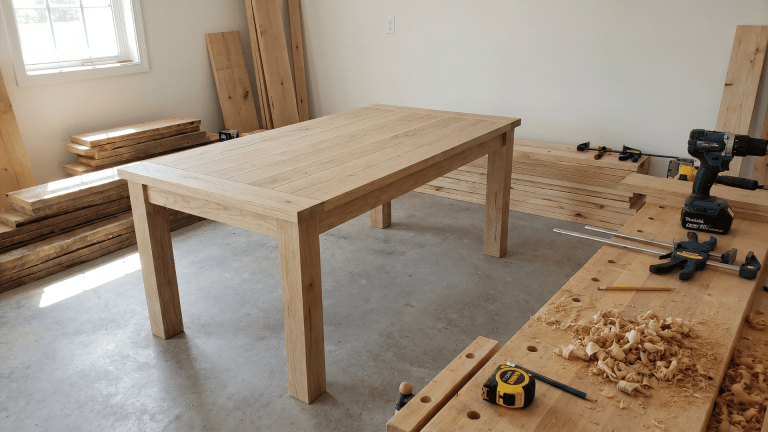 wood-farmhouse-table-in-a-workshop-with-cut-boards-and-basic-tools-nearby