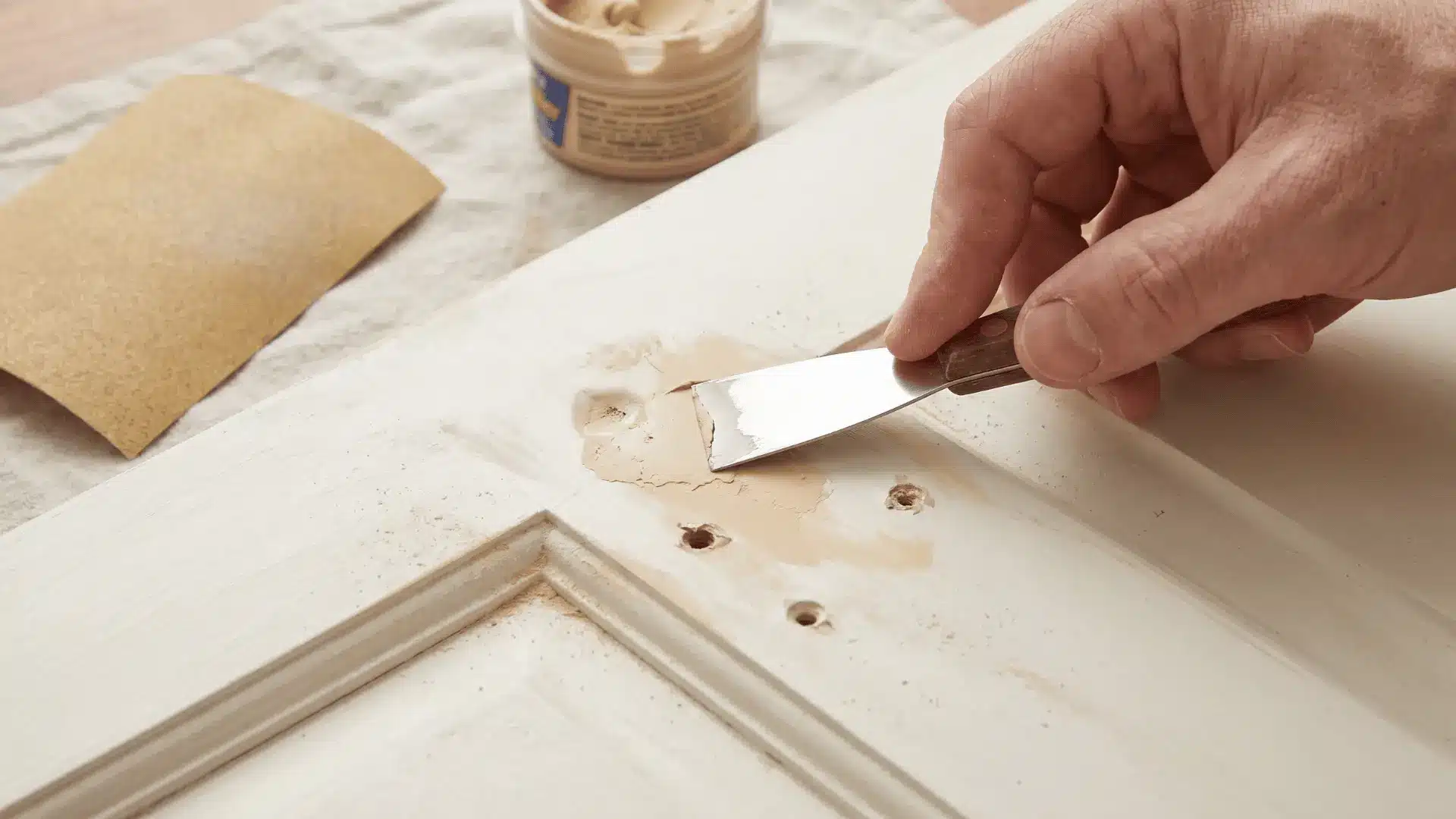 Wood filler applied to dents and old hardware holes on cabinet door