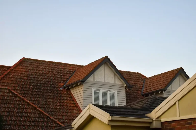 Gabled house rooftop with brown and gray shingles under clear blue sky