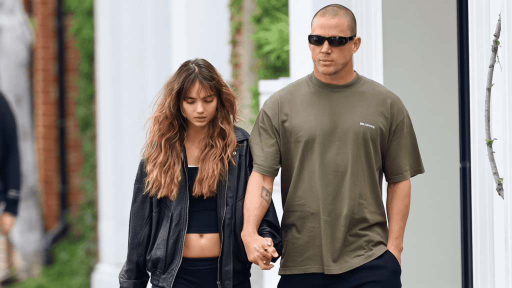 Channing Tatum in sunglasses and an olive tee holding hands with Inka Williams in a black leather jacket.