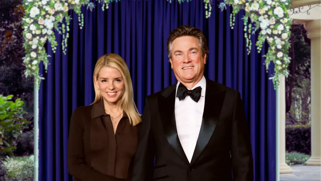 Pam Bondi and John Wakefield posing in formal attire at event with blue curtain backdrop.