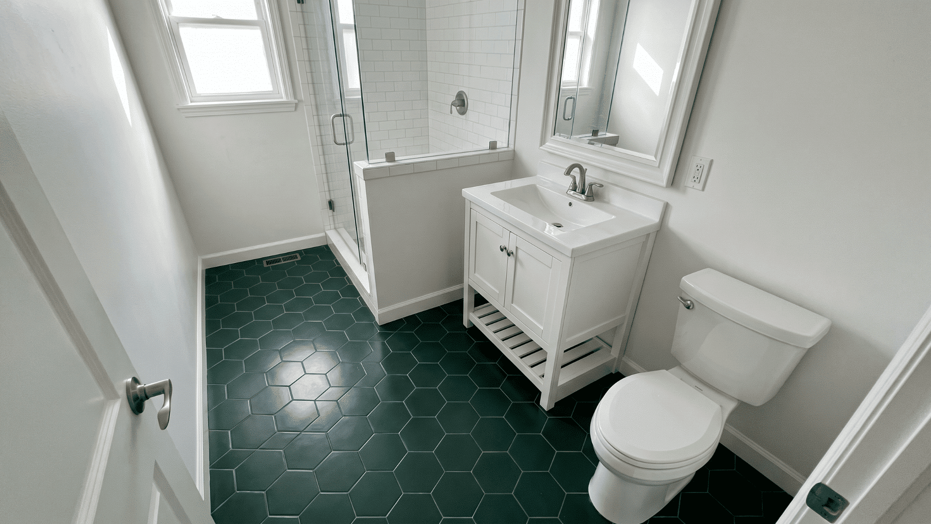 Bathroom with dark green hex tiles, white vanity, shower, mirror, and toilet.