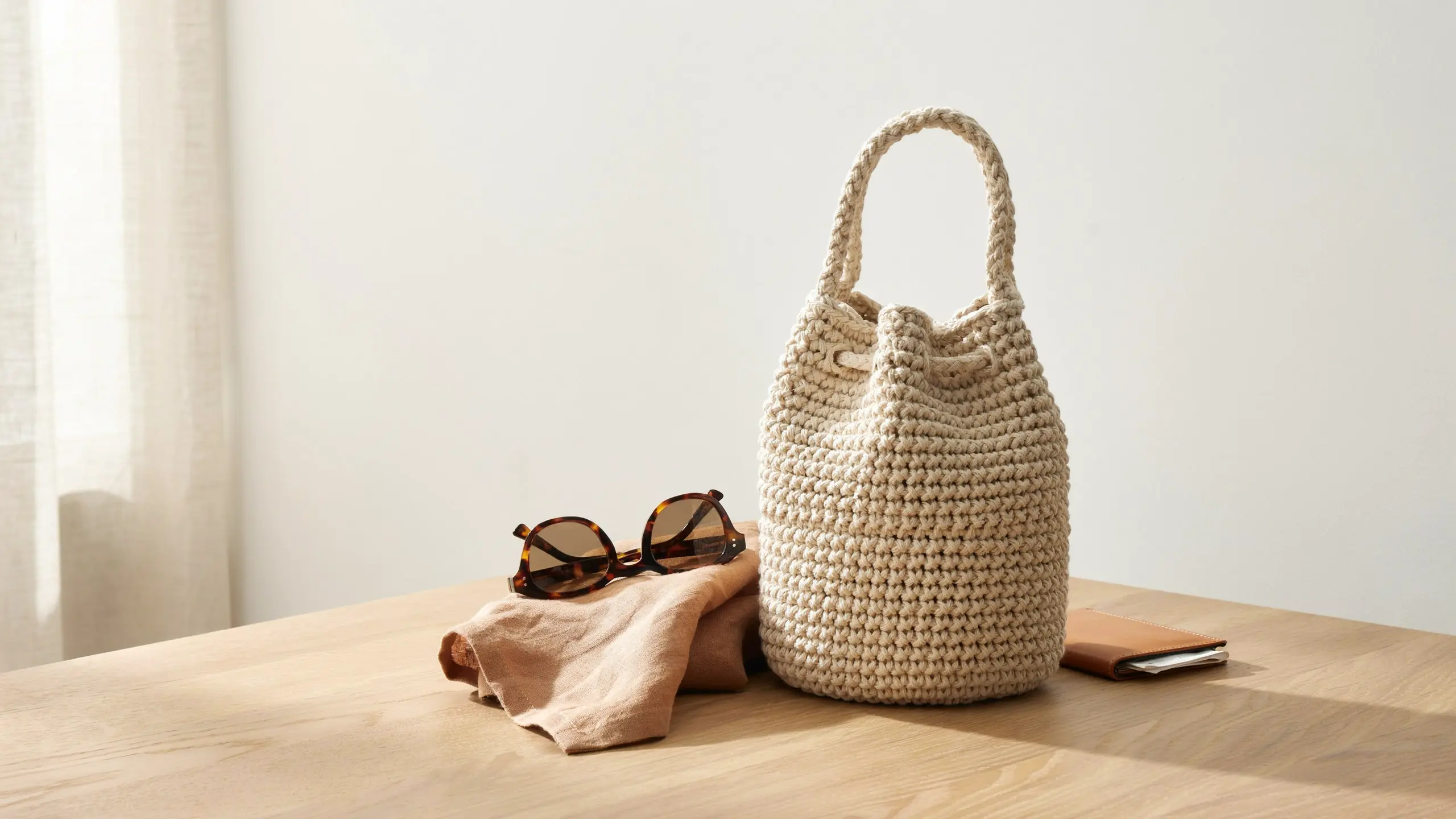 Round-base crochet bucket bag with drawstring top in a modern neutral style.