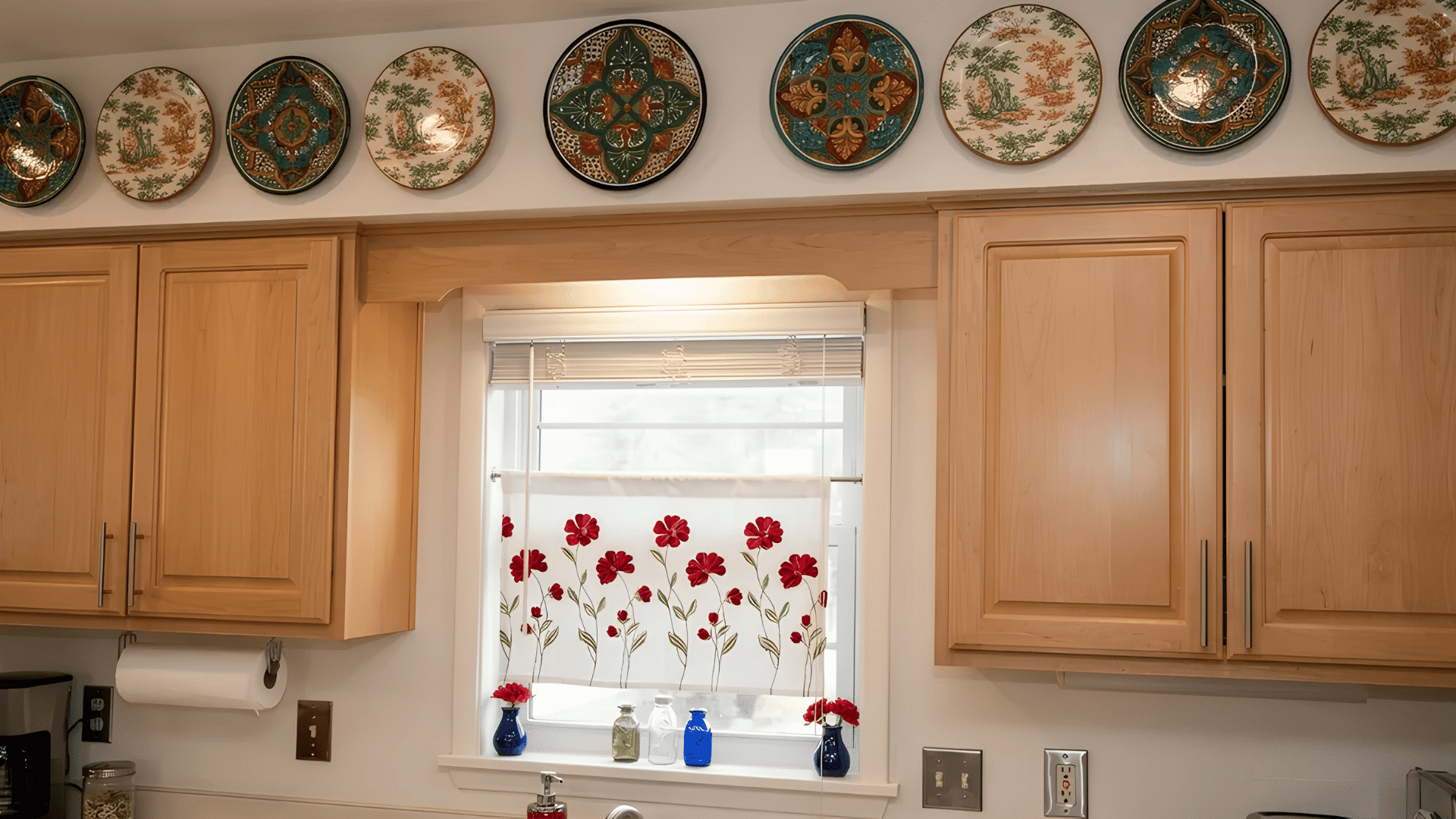 Decorative patterned plates arranged in a row above wooden kitchen cabinets.
