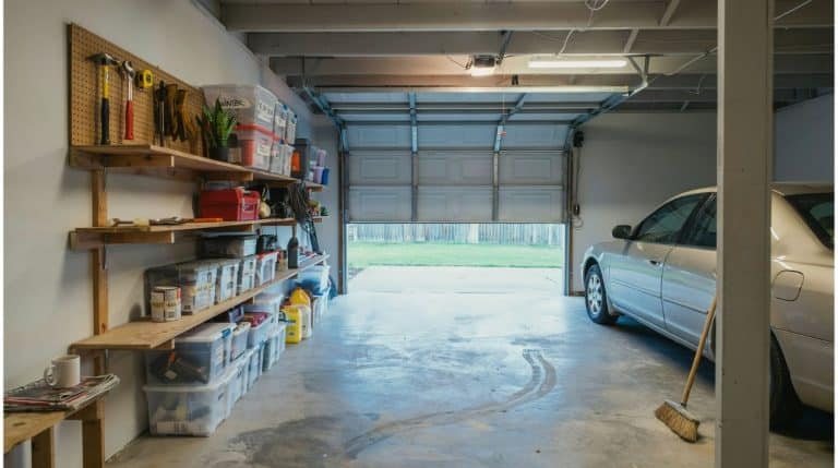 DIY garage shelves built from wood, mounted on the wall and holding labeled totes, tools, and paint cans in an organized garage.