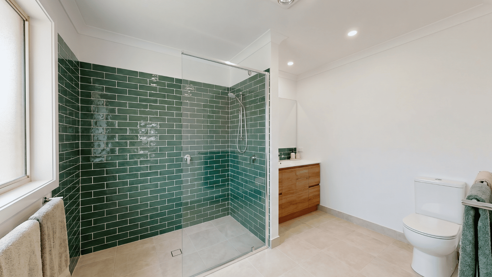 Forest green tiled shower with glass enclosure, white walls, vanity, and toilet. Description (slug format):