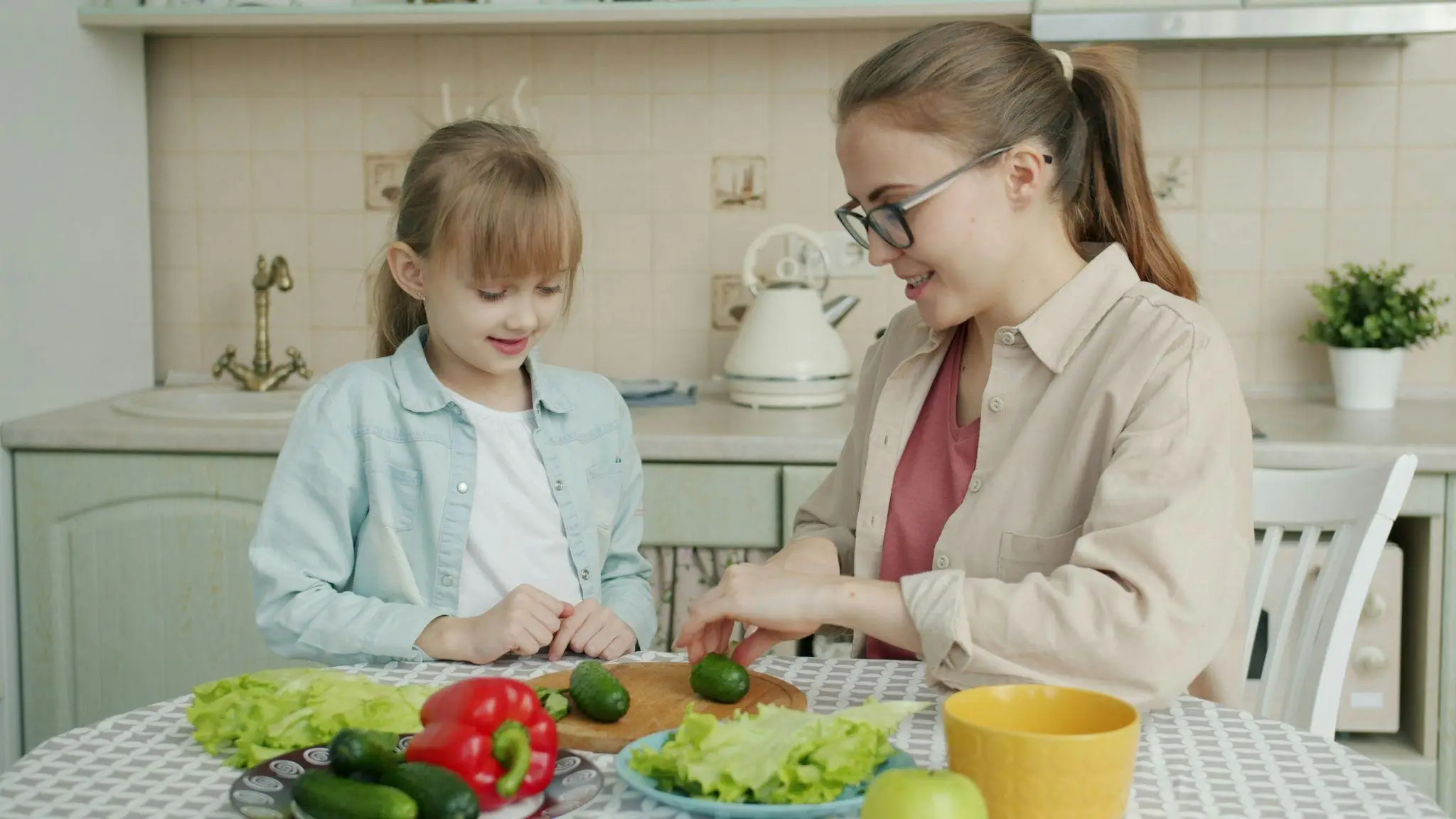 Mother and daughter preparing fresh vegetables at a kitchen table with cozy decor