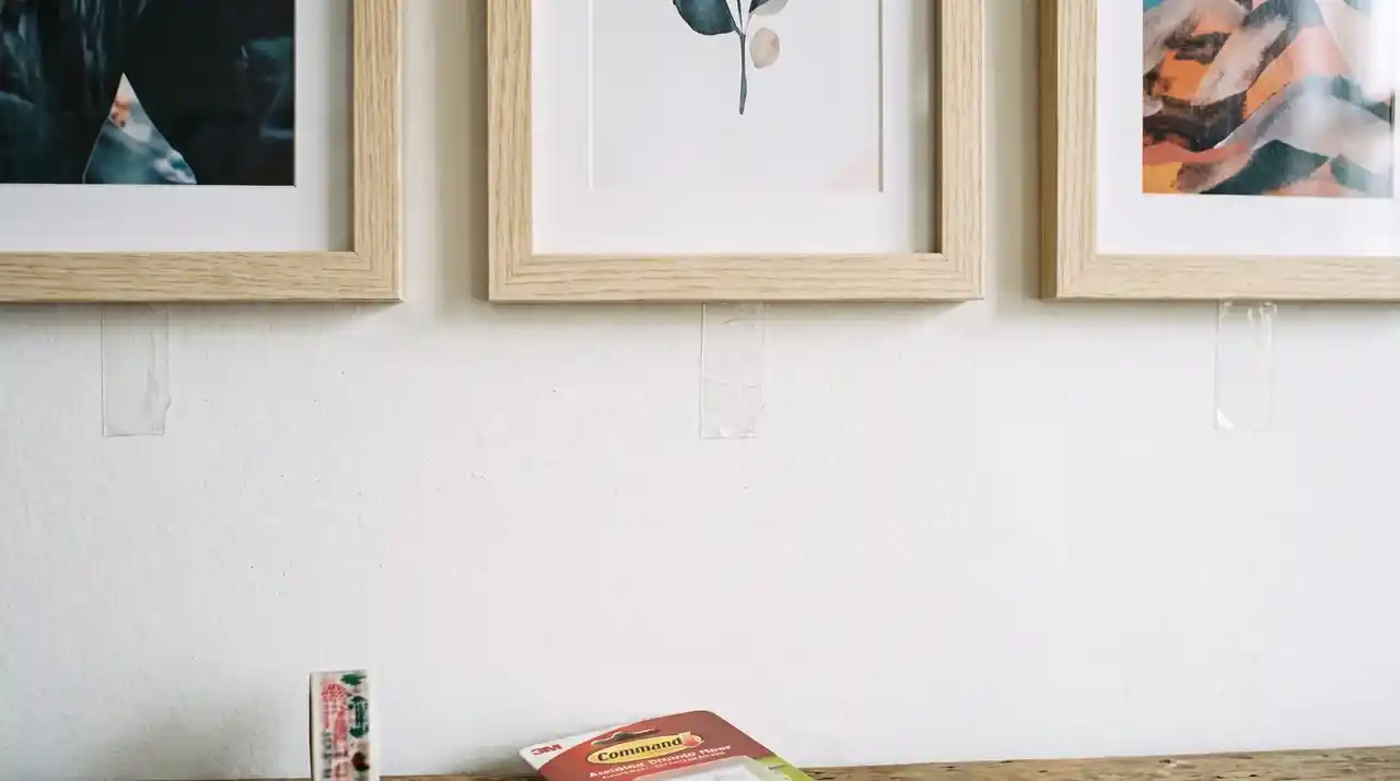 Frames on white wall with adhesive strips and washi tape showing how to hang pictures on wall without nails.