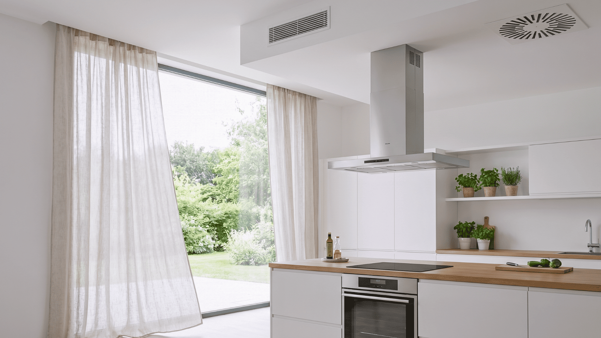 Bright kitchen with large window, light curtains, and chimney setup showing fresh airflow and ventilation design.