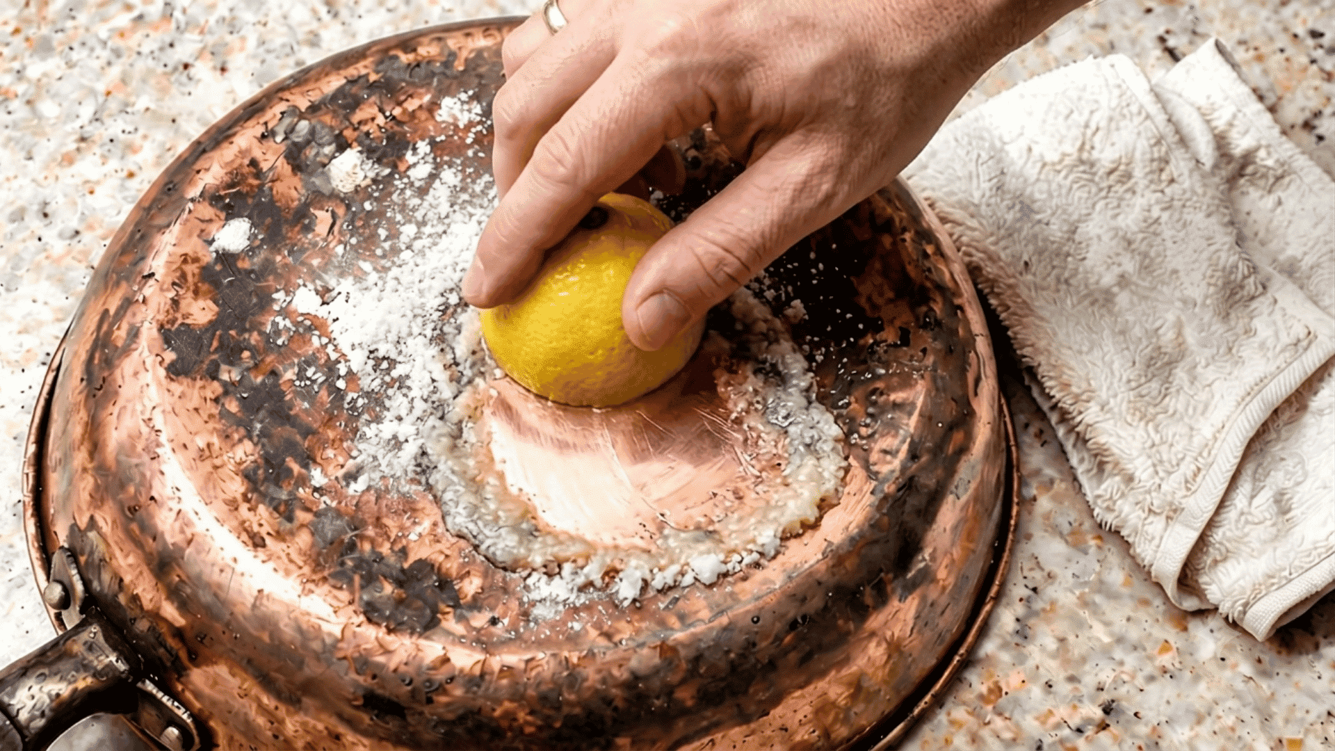 Hand rubbing lemon and salt on a tarnished copper pan surface