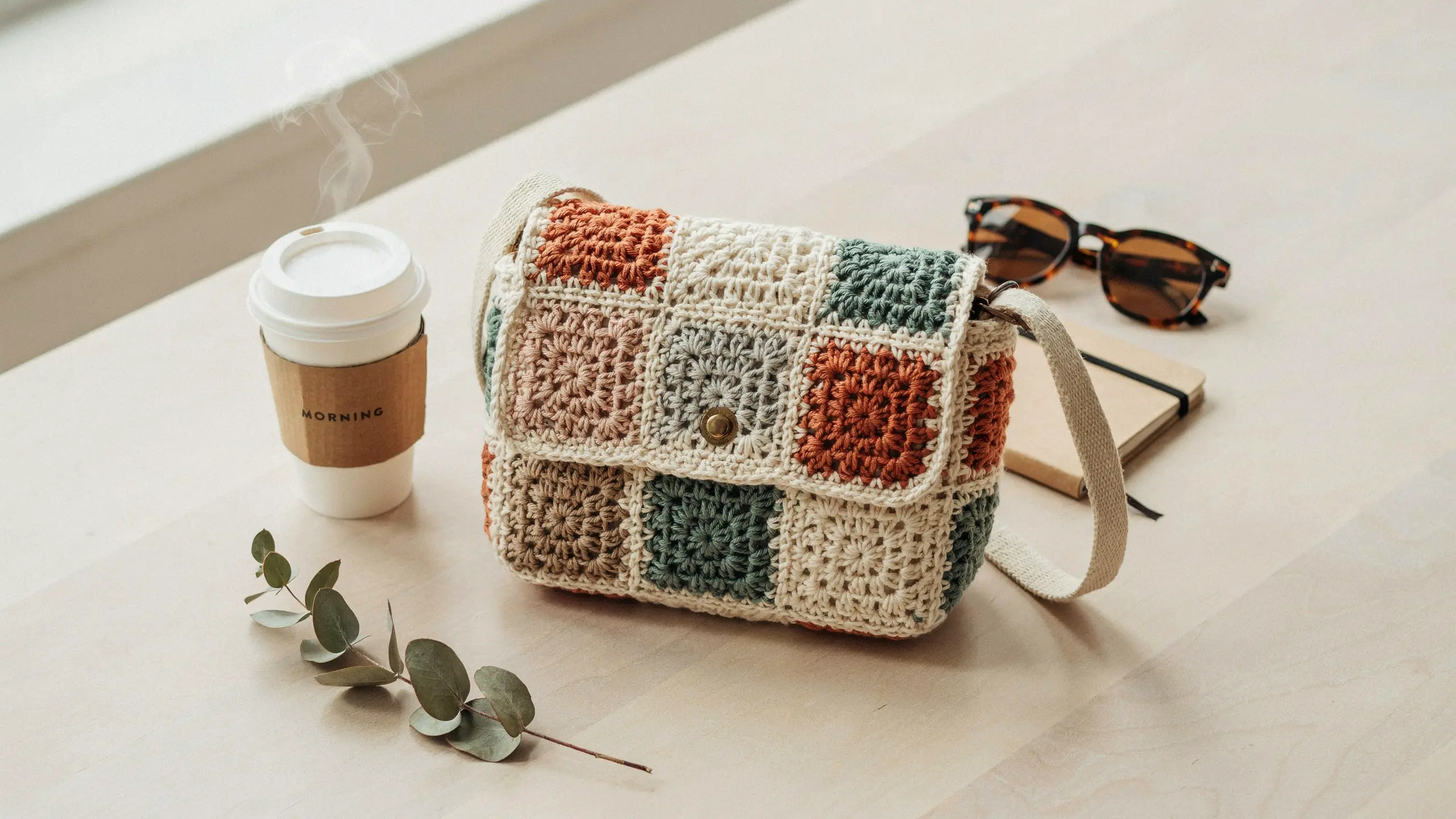 Granny square shoulder bag with flap closure and long strap in a modern style.