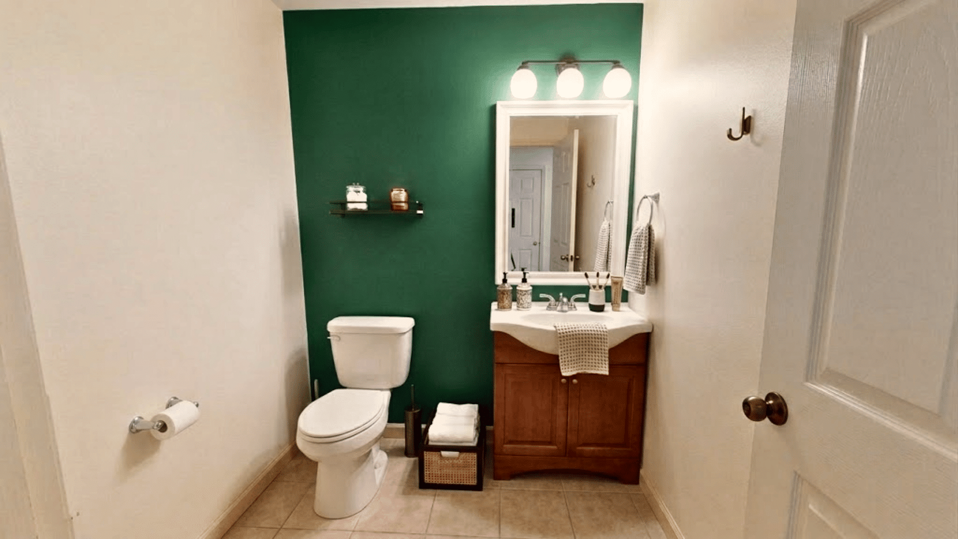 Bathroom with green accent wall, white fixtures, wood vanity, mirror, and toilet.