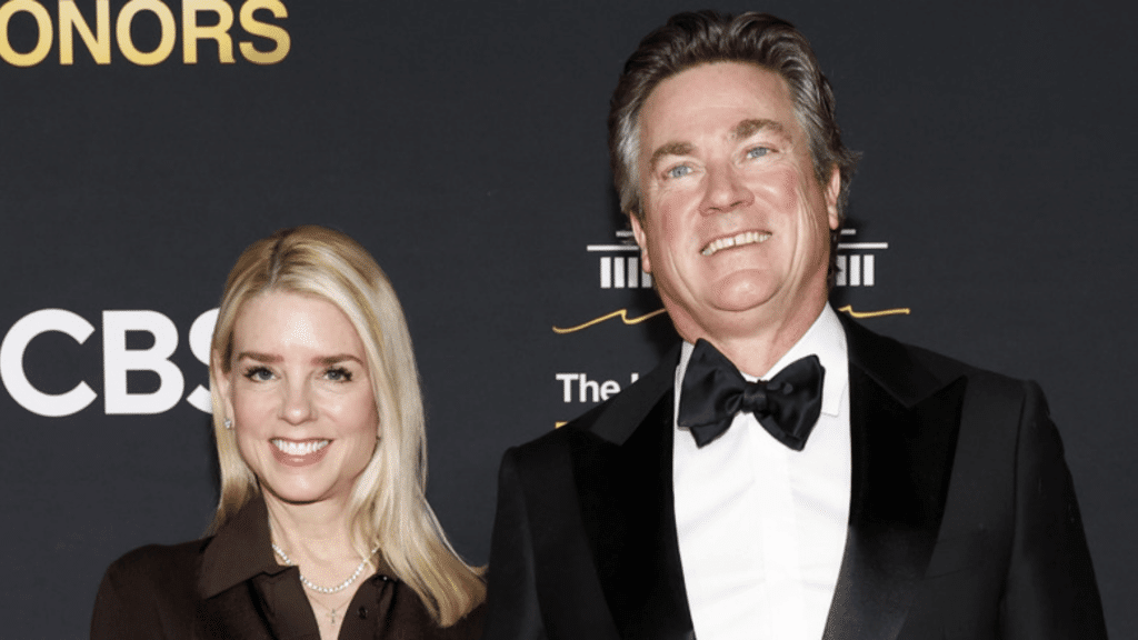 Two people standing together at an awards event, wearing formal black attire against a dark backdrop with event logos.