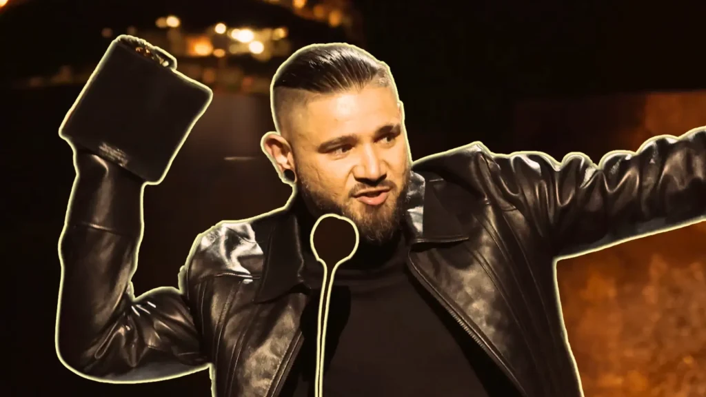 Skrillex holding a Grammy Award aloft in a leather jacket at an awards ceremony.