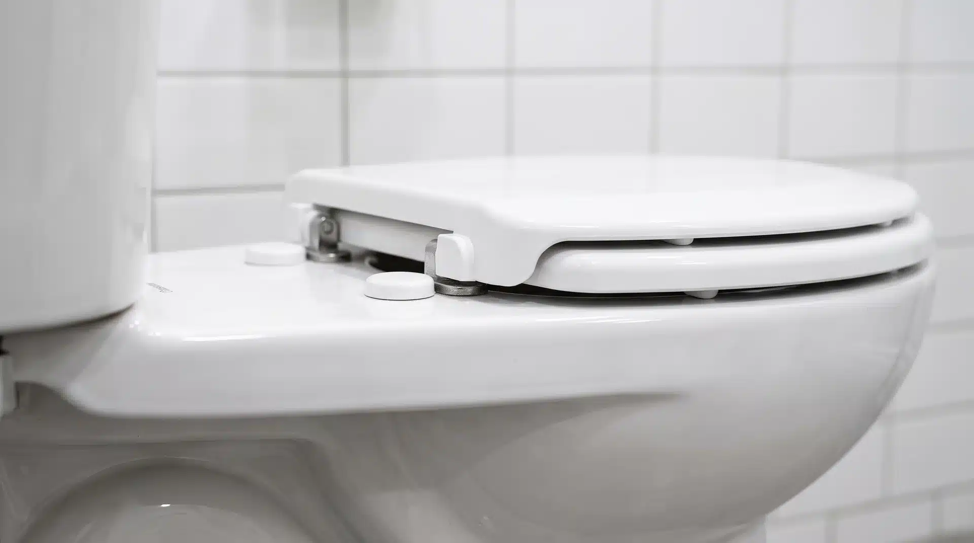 Hands demonstrating a toilet seat quick-release function with seat lifted from the hinge.