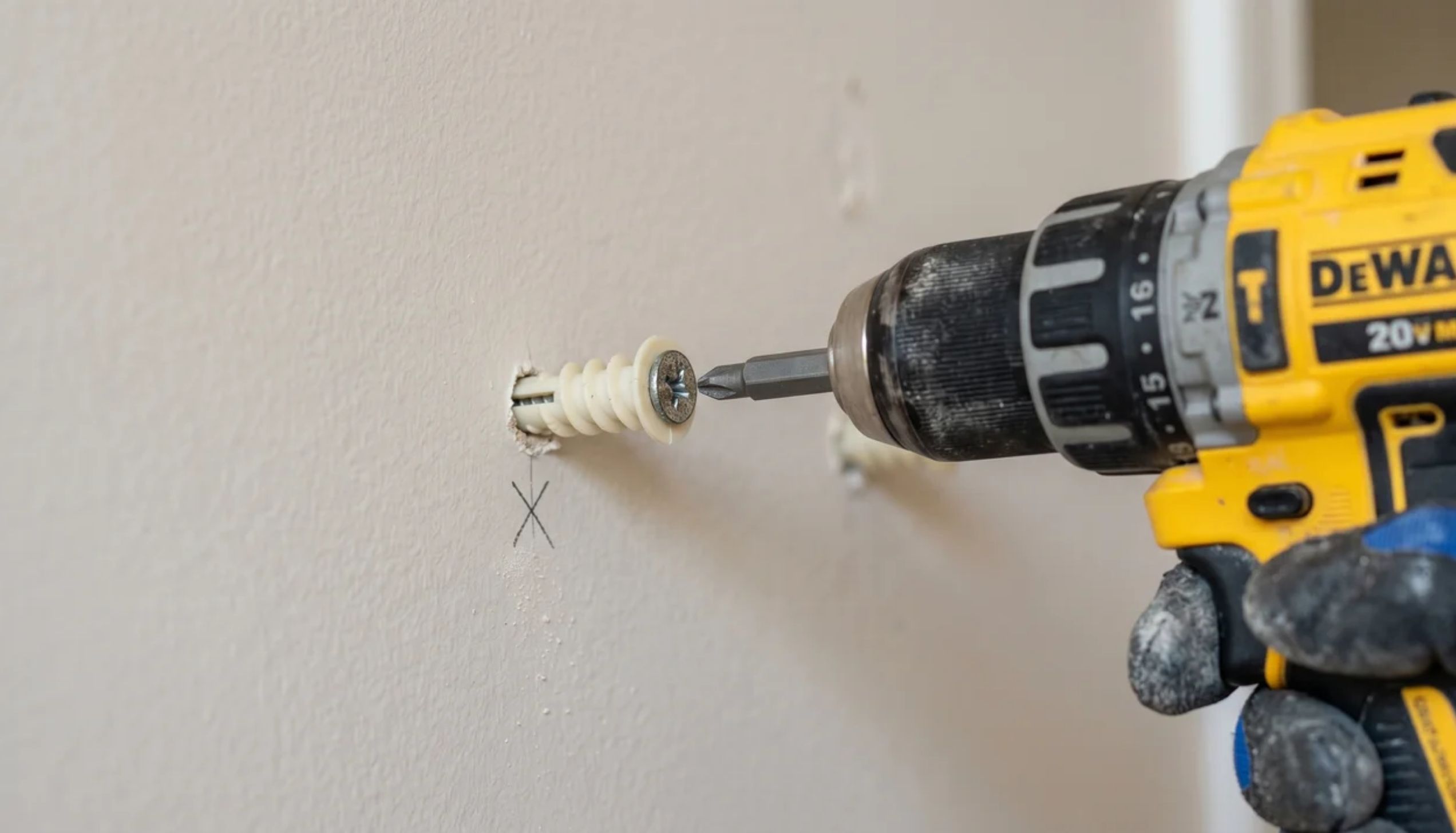 Drill inserting a drywall anchor into the wall during the process of how to hang a mirror securely