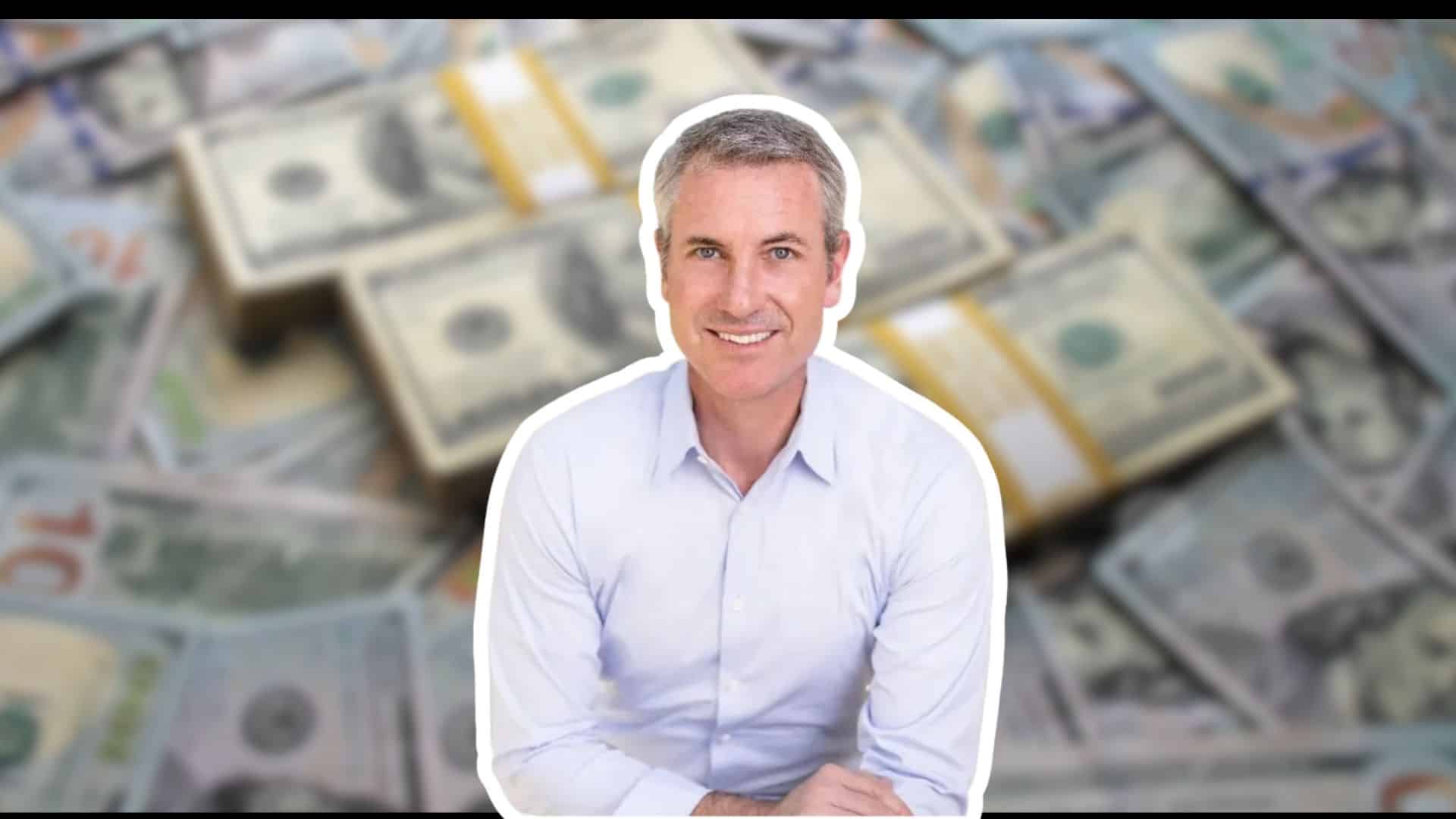 Andy Byron image in front of a blurred background of stacks of US dollar bills.