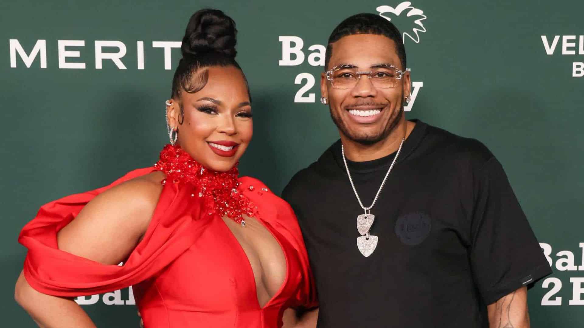 Ashanti in a red gown posing beside Nelly in black at a public event.