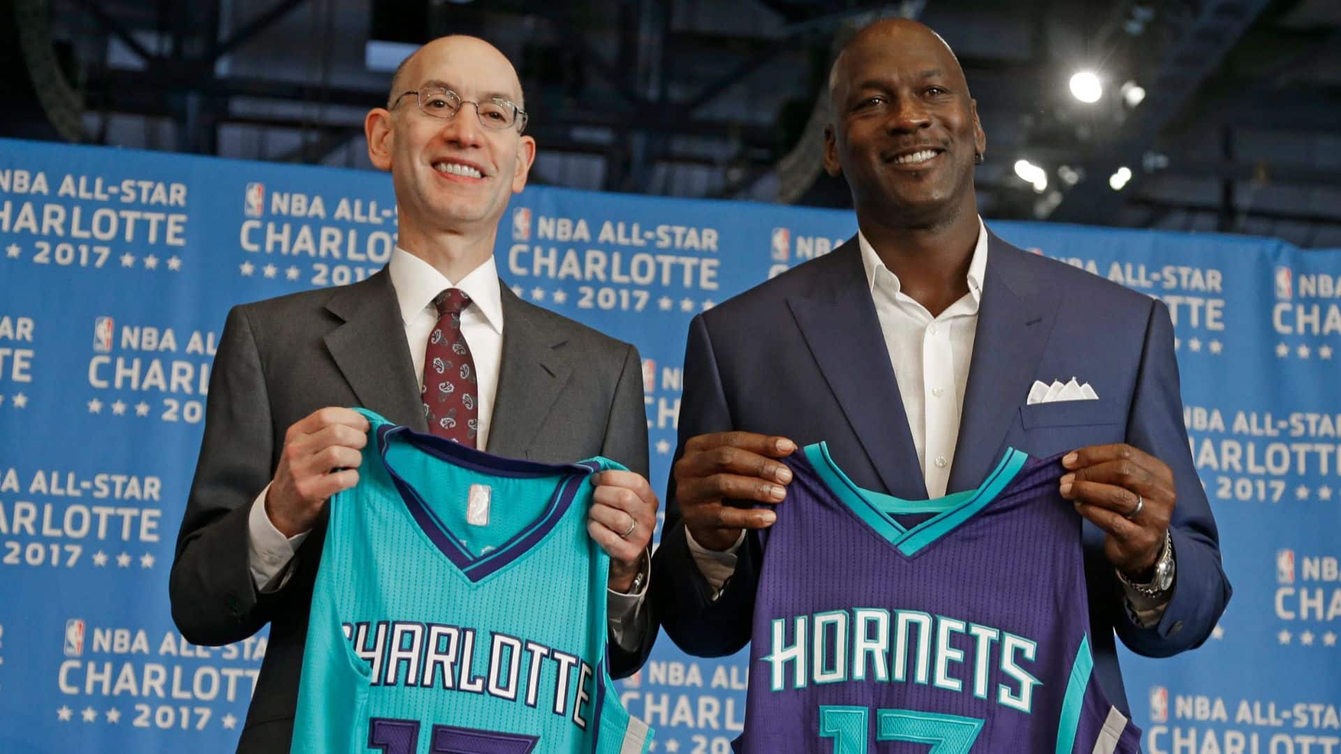 michael jordan holding Charlotte Hornets jerseys at an NBA All-Star event in Charlotte.