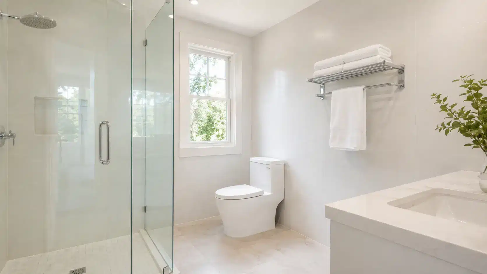 A spotless white bathroom with clean tiles and glass shower door, ready for a deep clean bathroom session.