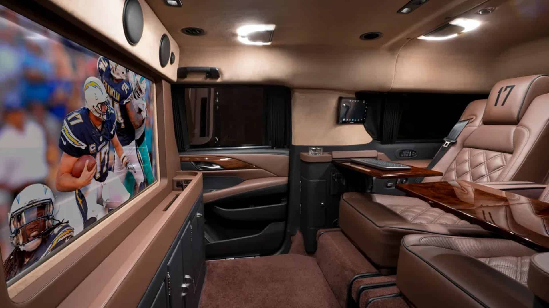 Interior of a customized luxury SUV equipped with seating and a large screen for studying football film