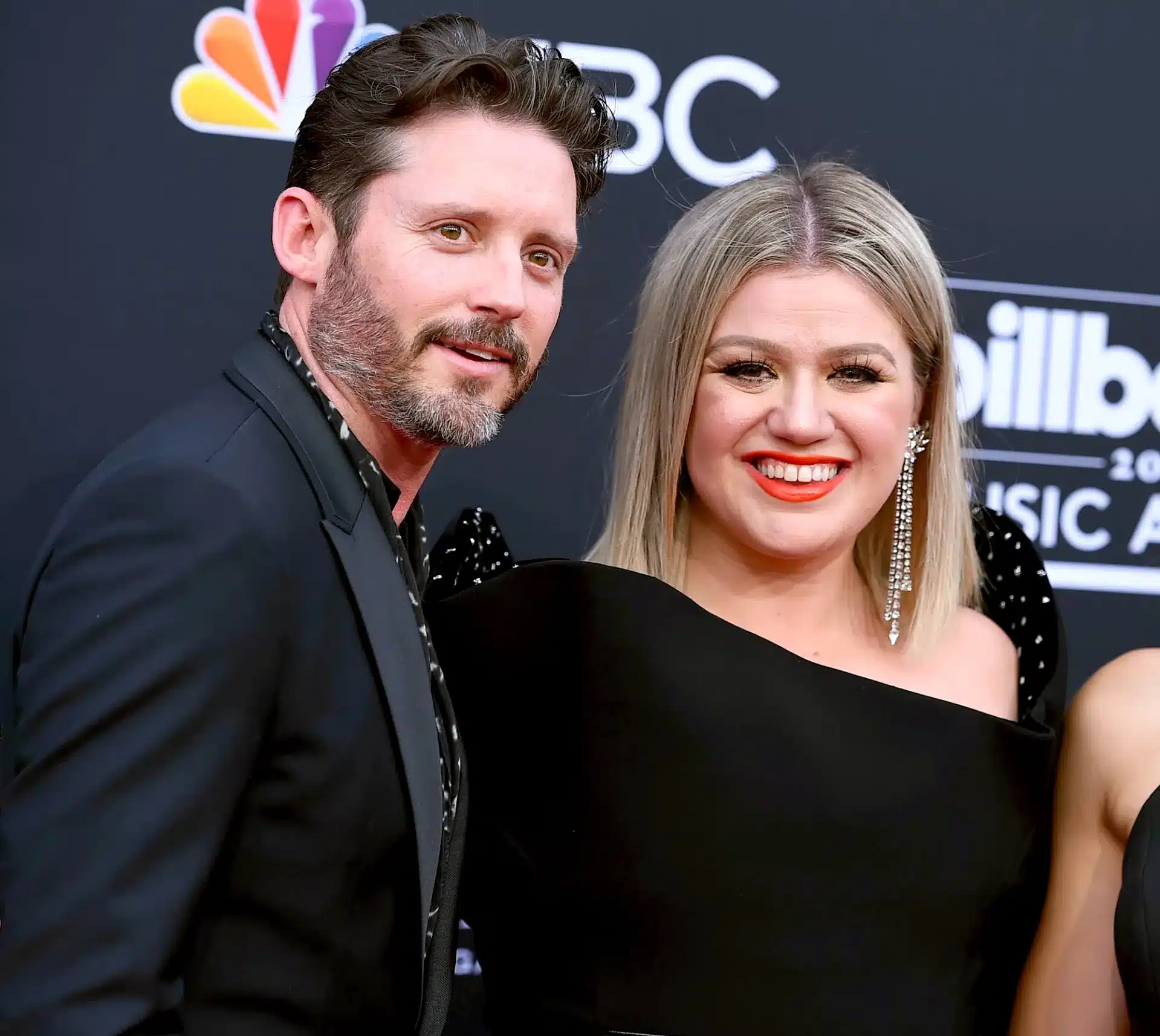 Kelly Clarkson and her ex-husband Brandon Blackstock posing together on a red carpet in front of a Billboard Music Awards backdrop.