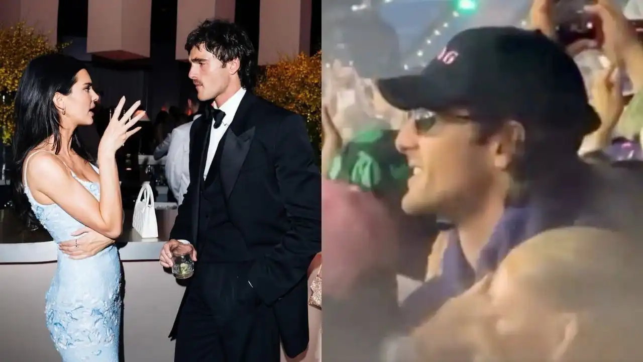 Kendall Jenner and Jacob Elordi talking at a party alongside a man in a cap.
