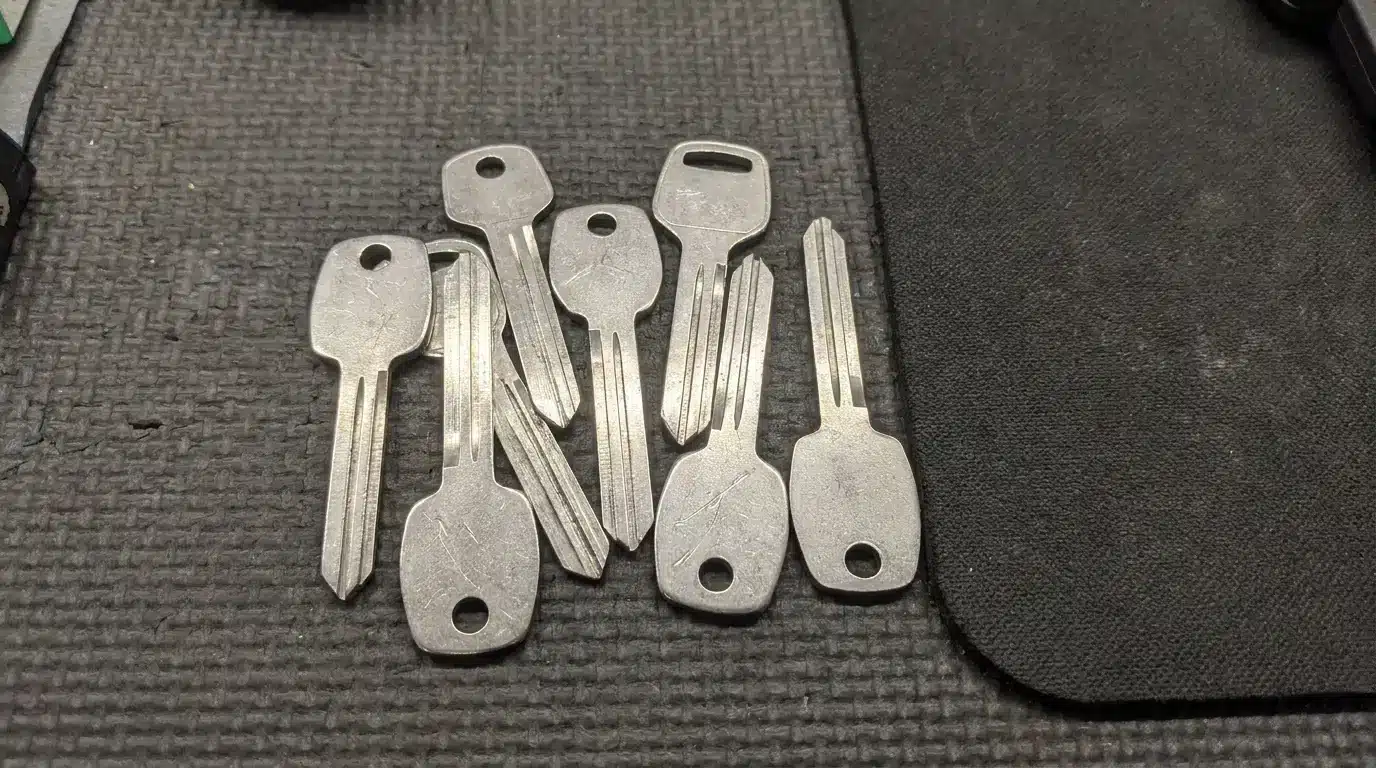 Seven uncut key blanks on textured black mat surface
