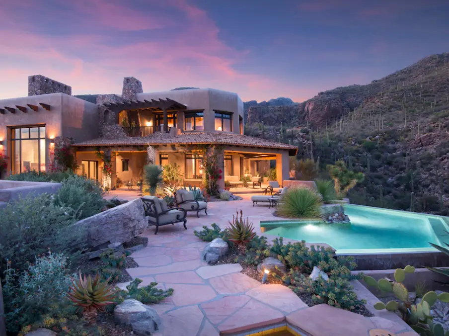 Luxury desert villa with infinity pool and outdoor seating at sunset in mountain landscape