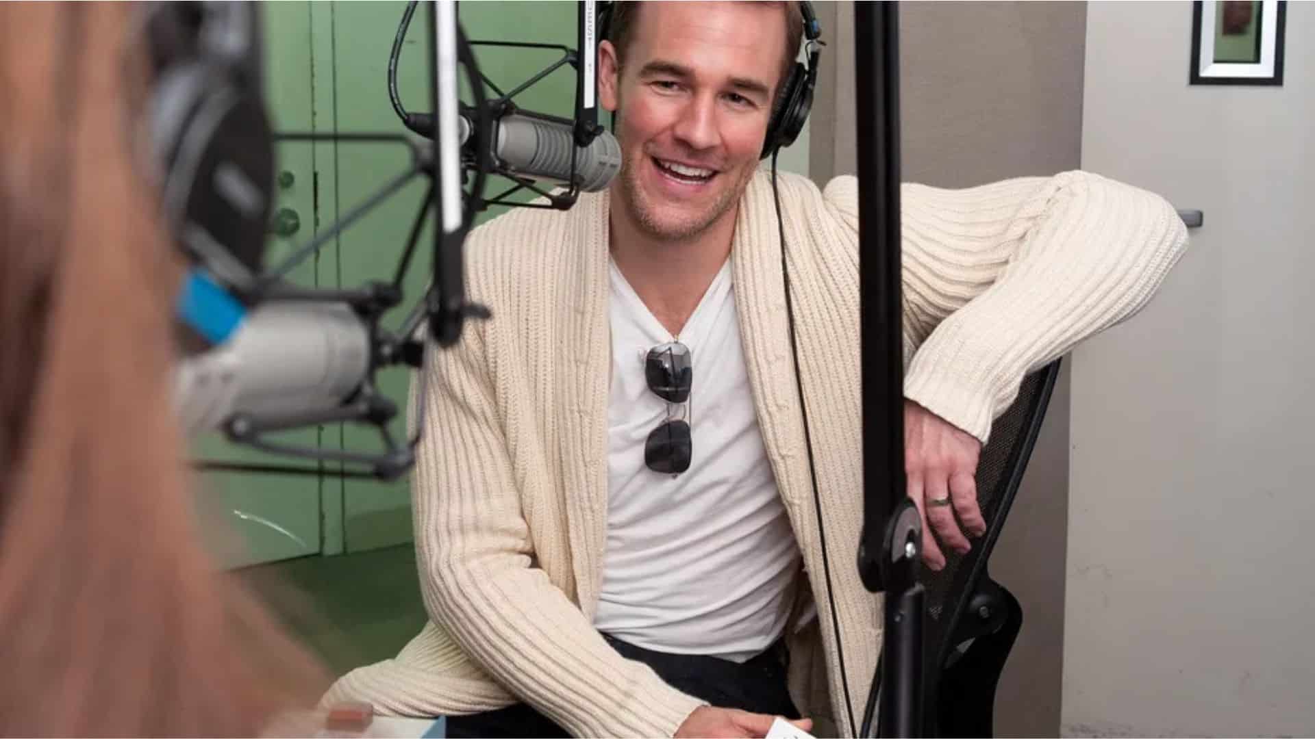 Male actor wearing headphones and speaking into a microphone during a radio studio interview.