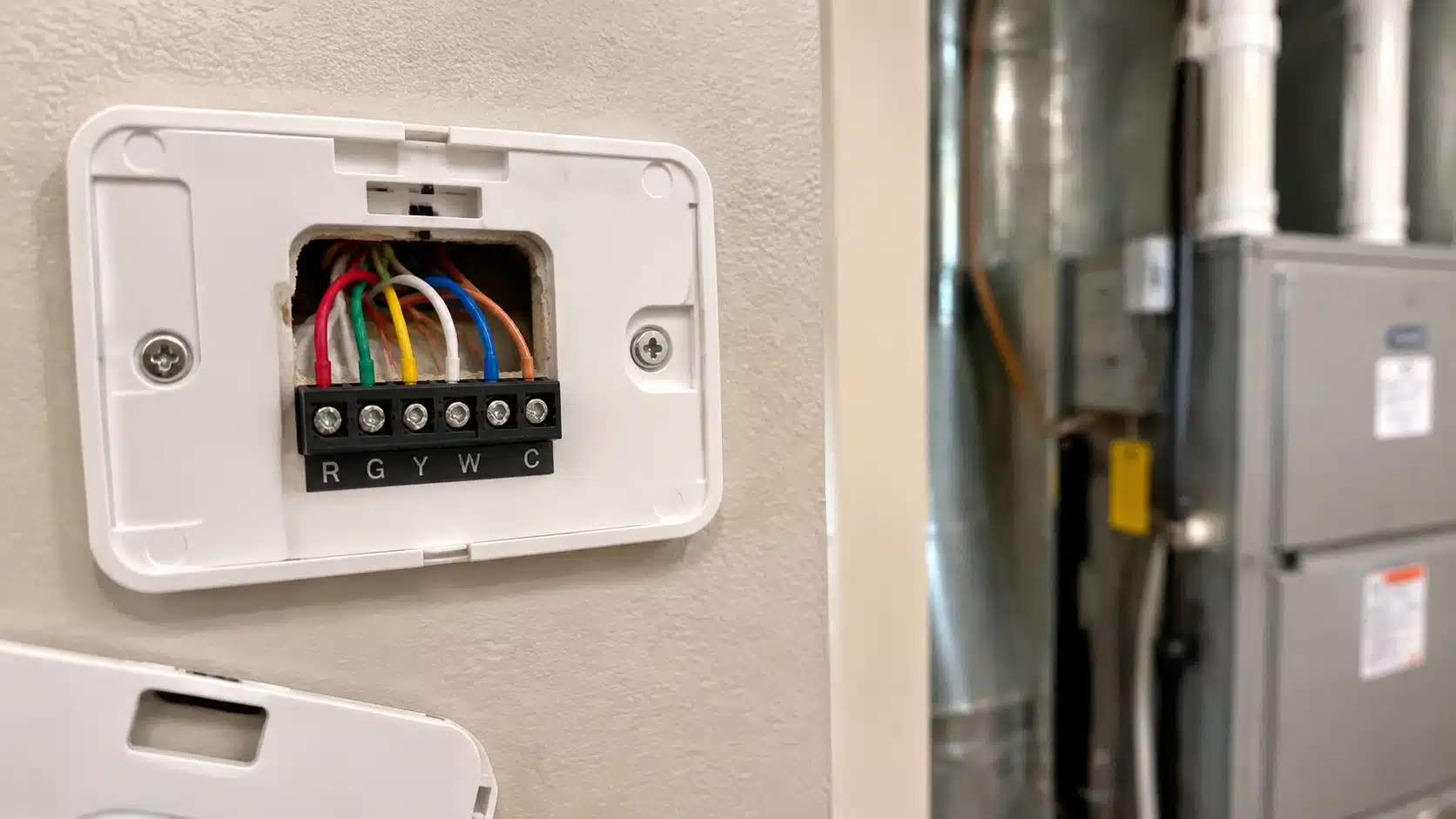 Open thermostat showing wiring connections for HVAC compatibility checking before installation.