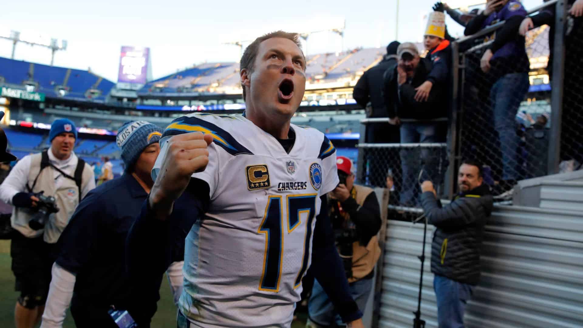 Philip Rivers celebrates with a raised fist near fans and photographers at a stadium.