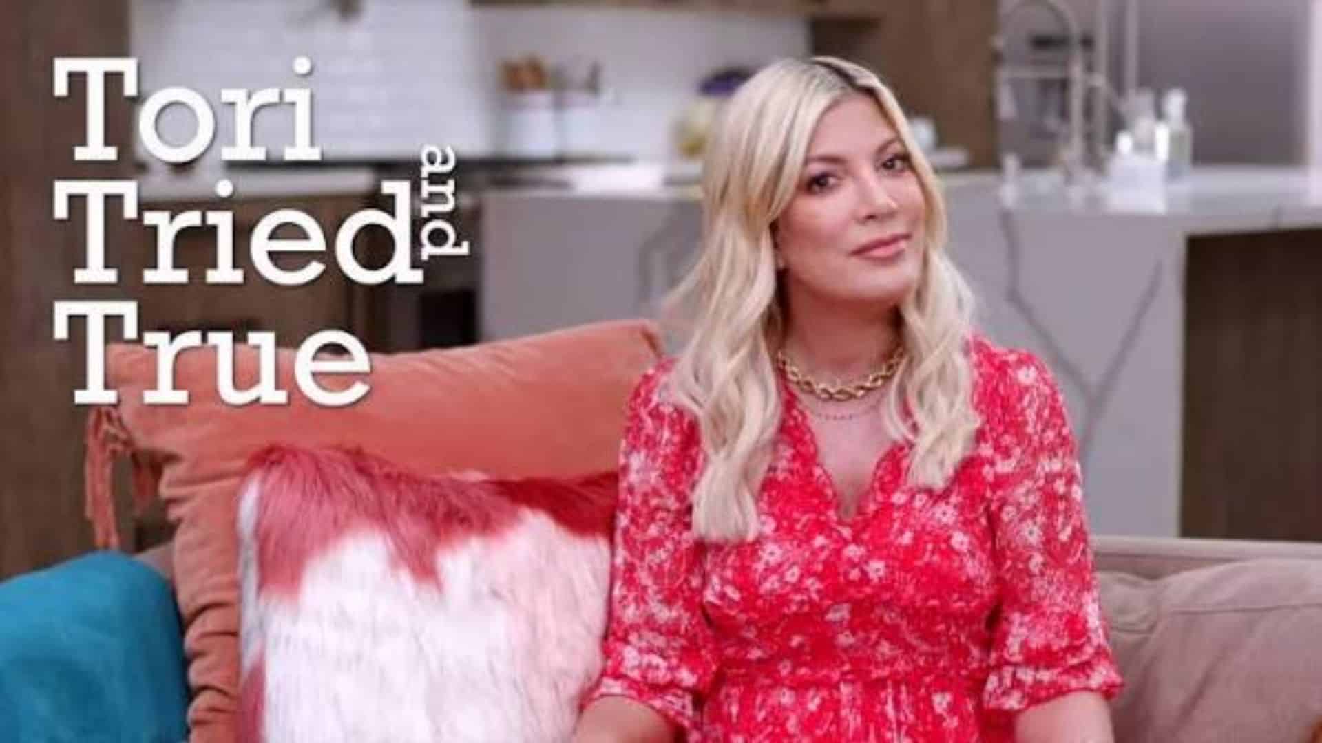 Tori Spelling sitting on a couch discussing financial struggles over the years