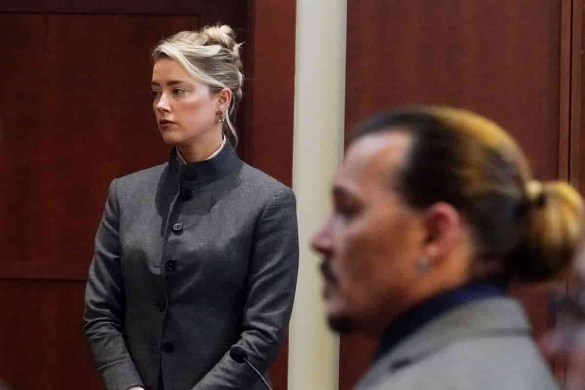 Woman in a gray suit standing in a courtroom with a blurred person in the foreground