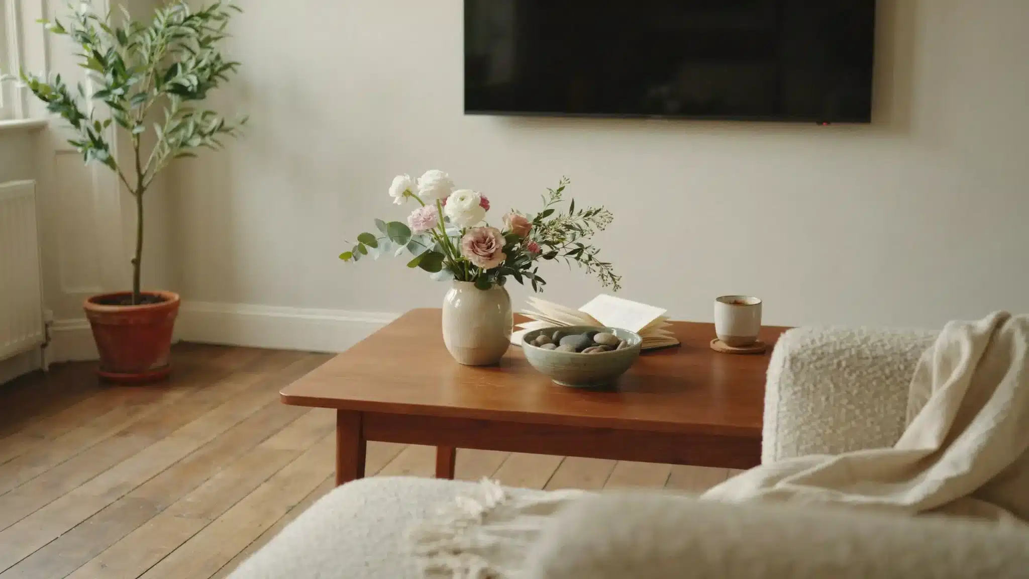 Fresh flowers and natural stones styling a wooden coffee table in a cozy living room.