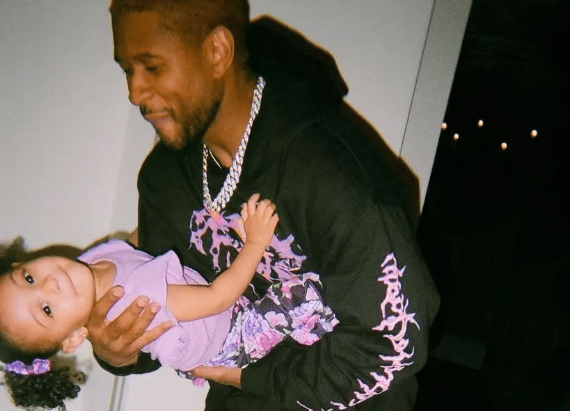 Usher holding his daughter, Sovereign, in his arms during a casual family moment.