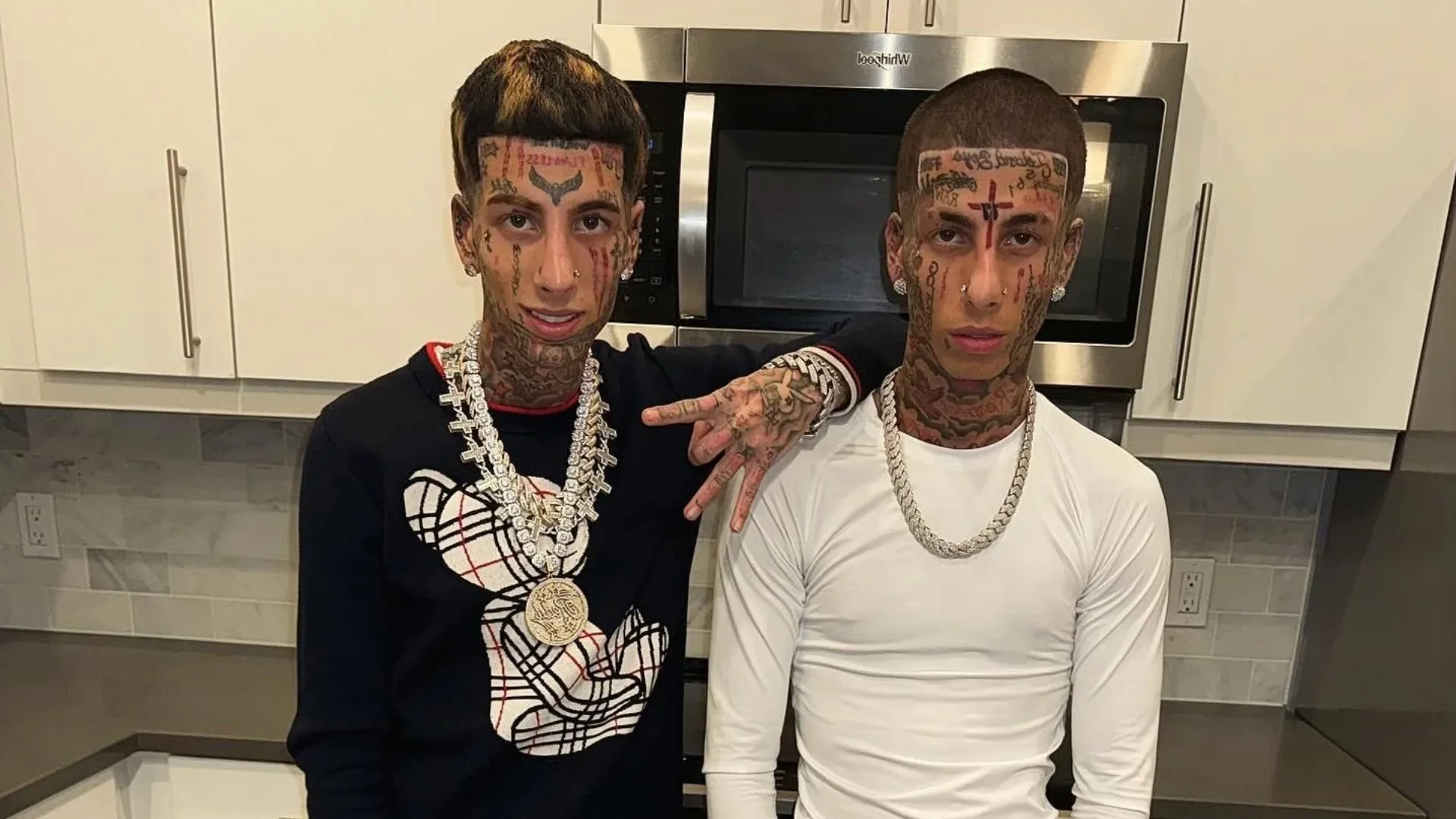 The Island Boys wearing diamond chains while posing together in a modern kitchen.